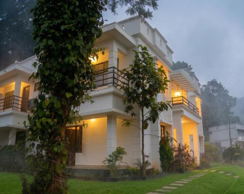 a large white building with a tree in front of it at Vythiri Palace Wayanad Pool Resort - Mist Climate & India's First Apple Infinity Pool in Vythiri