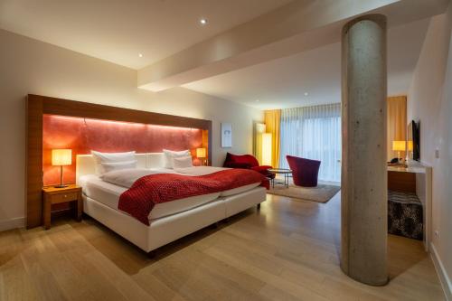 a bedroom with a large bed with a red blanket at Aqua Aurelia Suitenhotel an den Thermen in Baden-Baden