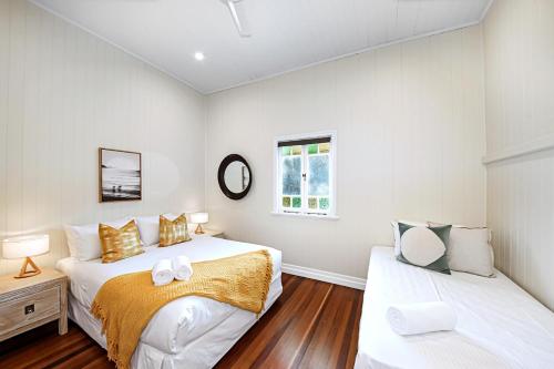 a white bedroom with two beds and a window at Kin Kin Farm House - Pets Allowed in Kin Kin