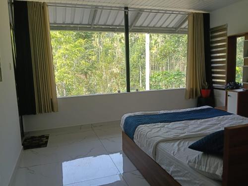 a bedroom with a bed and a large window at Quiet Canopy homestay in Padinjarathara