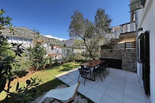 a patio with a table and chairs in a yard at Hibis, No 1 in Starigrad