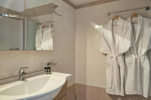 a white bathroom with a sink and a mirror at Skiathos Living by GHH in Skiathos