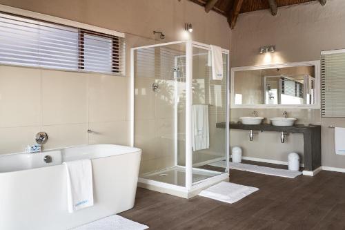 a bathroom with a shower and a tub and a sink at Crawfords Beach Lodge in Chintsa