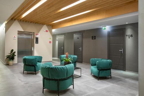 a waiting room with green chairs and elevators at CUBIK inn Design Rooms in Gravina di Catania
