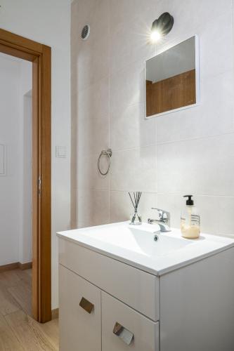 a bathroom with a white sink and a mirror at Na Casa da Fátima in Vila Nova de Milfontes