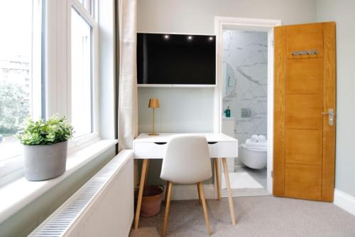 a bathroom with a desk and a toilet and a television at Farringdon Rooms in London
