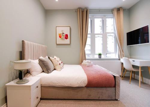 a bedroom with a bed with a desk and a window at Farringdon Rooms in London