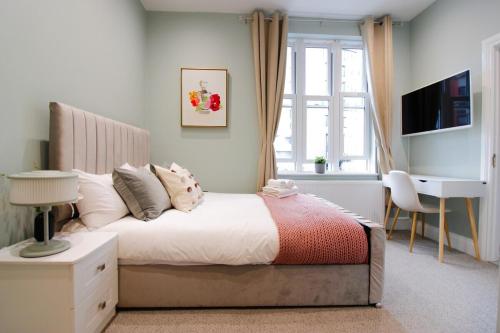a bedroom with a bed with a desk and a window at Farringdon Rooms in London