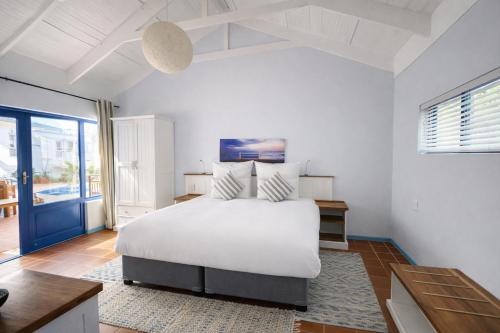 a white bedroom with a bed and a large window at BlueSky Arniston Boutique Guesthouse in Arniston