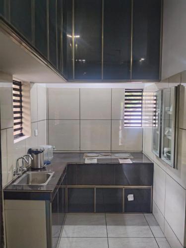 a kitchen with black cabinets and a sink at Feliz Homes Kottakkal in Kottakkal