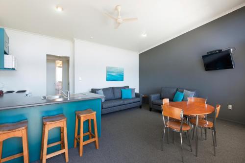 a kitchen and a living room with a table and chairs at Beach House Motel in Papamoa