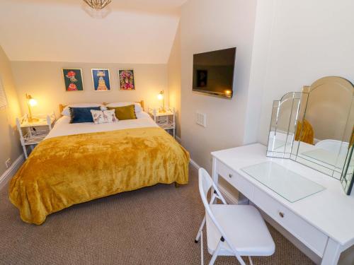a bedroom with a bed and a desk with a mirror at Fern Cottage in Lichfield