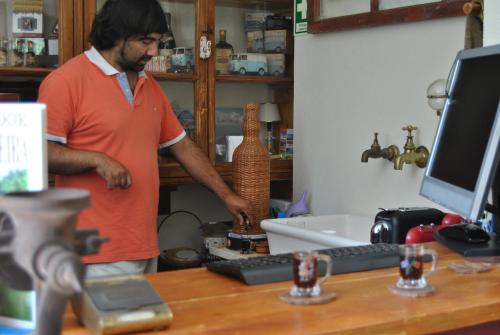 a man standing in front of a desk with a computer at A Casa Estrelícia-Dourada Garcês in São Vicente