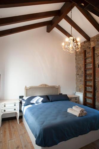 a bedroom with a blue bed and a chandelier at Aticos La Riba in Luanco