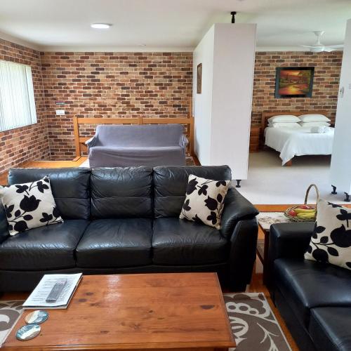 a living room with a black leather couch at Emerald Tropical Palms B & B in Emerald Beach