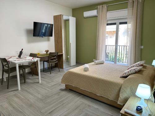 a bedroom with a bed and a table and a dining room at Ferrera Suite & Rooms in Misterbianco