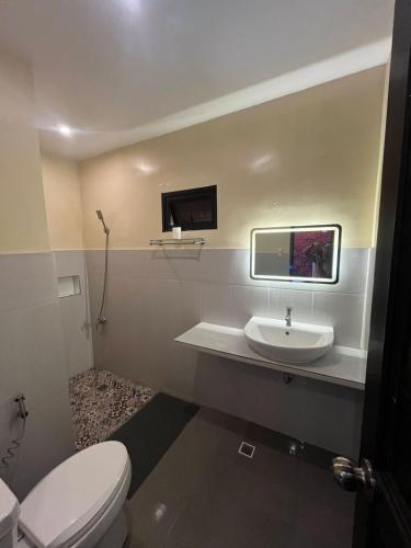 a bathroom with a white toilet and a sink at Witty Woods Guesthouse in Camalig