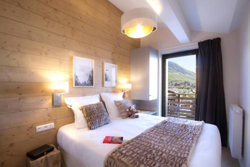 a bedroom with a large bed with a large window at Résidence Odalys l'Éclose in L'Alpe-d'Huez