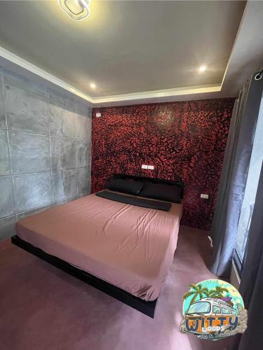 a bedroom with a bed and a red brick wall at Witty Woods Guesthouse in Camalig