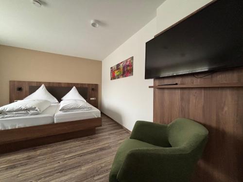 a bedroom with a bed and a green chair at Hotel Krone Neuenburg in Neuenburg am Rhein