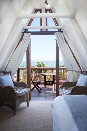 a bedroom with two beds and a view of the ocean at Crawfords Beach Lodge in Chintsa