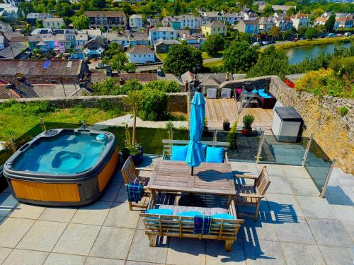 a patio with a wooden table and a swimming pool at High Cross House in Millbrook
