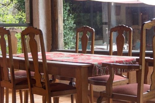 a wooden table with four chairs and a table with a red table cloth at Lares De Chacras in Chacras de Coria