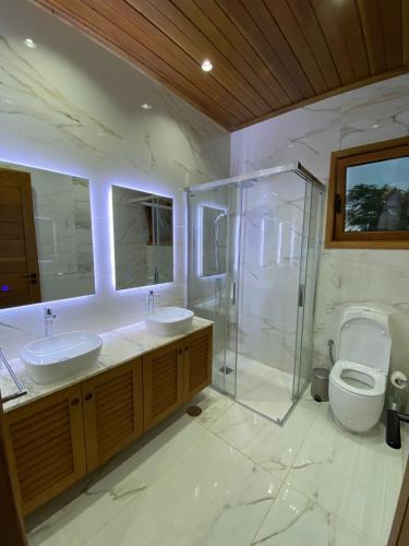 a bathroom with two sinks and a shower and a toilet at Moradia Pérola da Natureza in Lemos