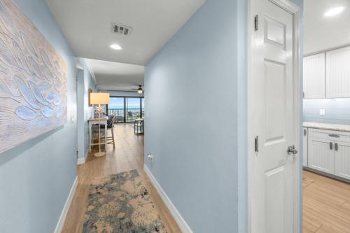 a hallway with a white door and a kitchen at Sunset Captiva Bayside Unit 103 condo in Captiva