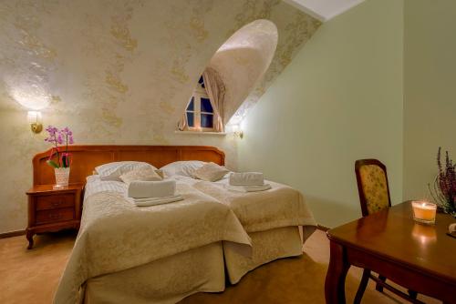 a bedroom with a bed and a table and a window at Hotel Dwór Fijewo in Golub-Dobrzyń