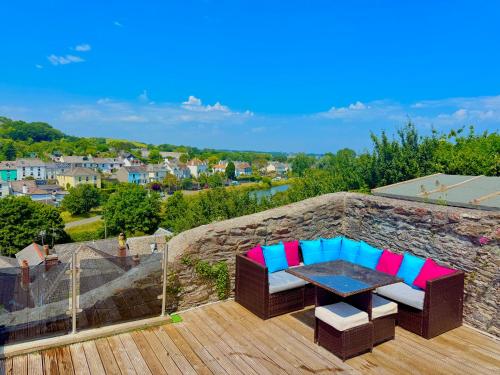 a patio with a table and chairs on a stone wall at High Cross House in Millbrook