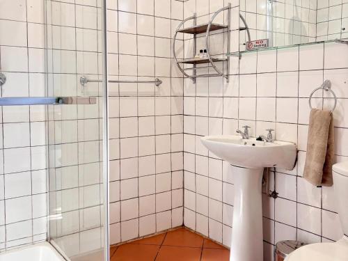 a white tiled bathroom with a sink and a shower at Hendersons Lodge Ltd in Senekal