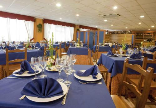 a dining room with blue tables with glasses and napkins at Casa San Martiño - Teo in Rua De Francos