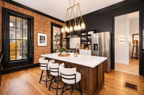 a kitchen with a bar with stools and a refrigerator at Charming 7BR Home Bourbon Trail & Attractions in Louisville