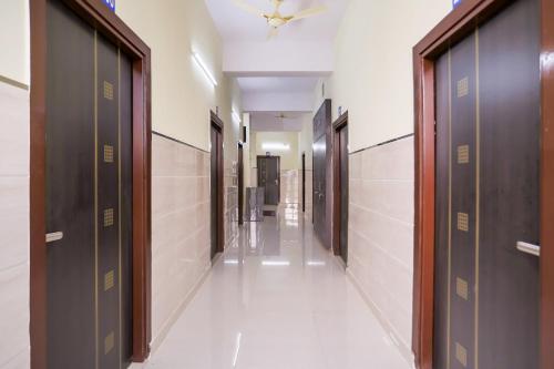 a hallway with brown doors and white tile walls at Super Hotel O Viraj Deluxe Narela in Delhi