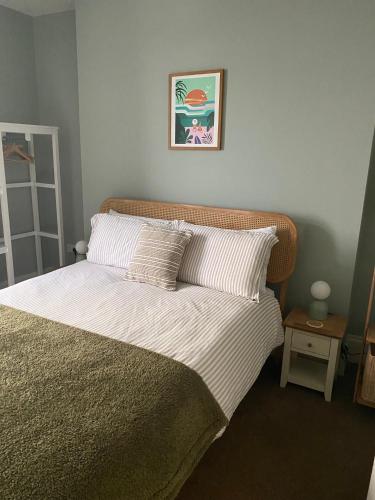 a bed with two pillows and a picture on the wall at Spacious flat - fabulous sea views & walk to beach in Woolacombe