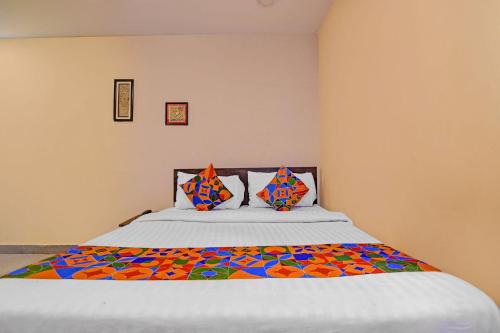 a bedroom with a large bed with colorful sheets and pillows at FabHotel The Crown Aura in kolkata