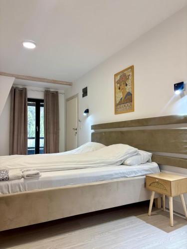a bedroom with a large bed and a table at Apartmani Terase in Konjska Reka