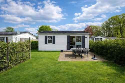 a white house with a table in a yard at 75, Relax - Nature - Cycling - Hiking - Central! - Leisure only in Oisterwijk