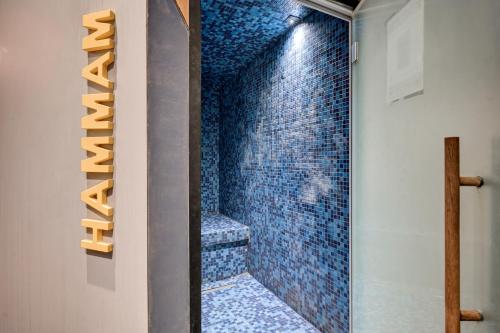 a bathroom with a blue tiled shower with a glass door at Alex Hotel & Spa in Marseille