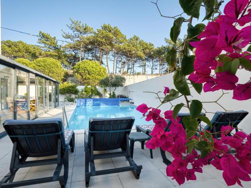 a patio with a table and chairs and pink flowers at Maresia Villa Mar in Nazaré