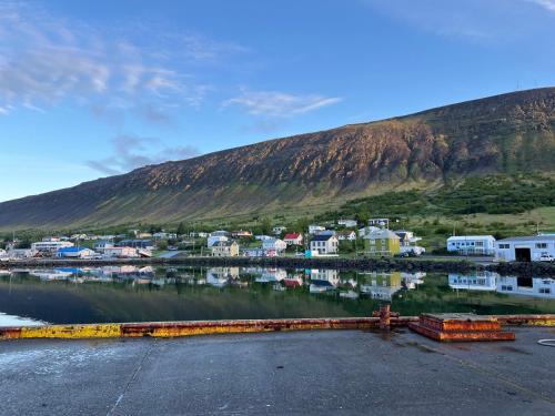 a small town next to a body of water with a mountain at KEX Þingeyri in Þingeyri