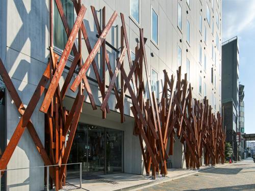 a building with a bunch of wooden art on the sidewalk at ONE@Tokyo by insomnia in Tokyo