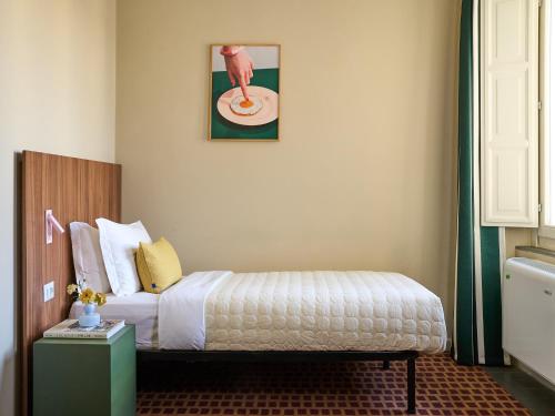 a bedroom with a bed with a table and a picture at Numa Florence Rodo in Florence