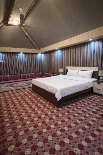 a bedroom with a large bed and red carpet at Holly Hills Guesthouse Ras Al Jinz in Junayz al Janūbī