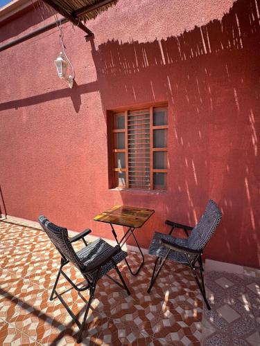 two chairs and a table in front of a building at Holly Hills Guesthouse Ras Al Jinz in Junayz al Janūbī
