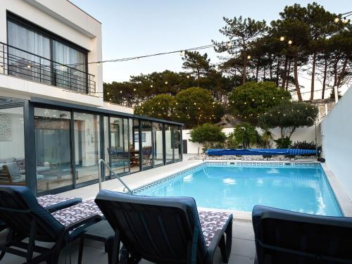 a swimming pool with chairs and a building at Maresia Villa Mar in Nazaré