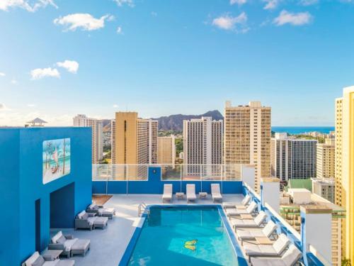 a view from the rooftop of a building with a swimming pool and chairs at Pacific Monarch Hotel in Honolulu