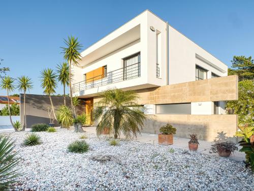 a white house with palm trees in front of it at Maresia Villa Mar in Nazaré