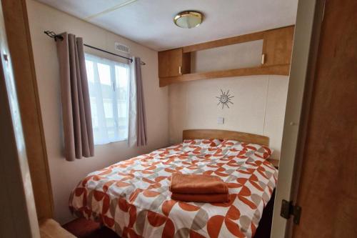 a bedroom with a bed with a orange and white comforter at Palm Court - 3 Bed Heated Pool Parking Nr Beach in Par